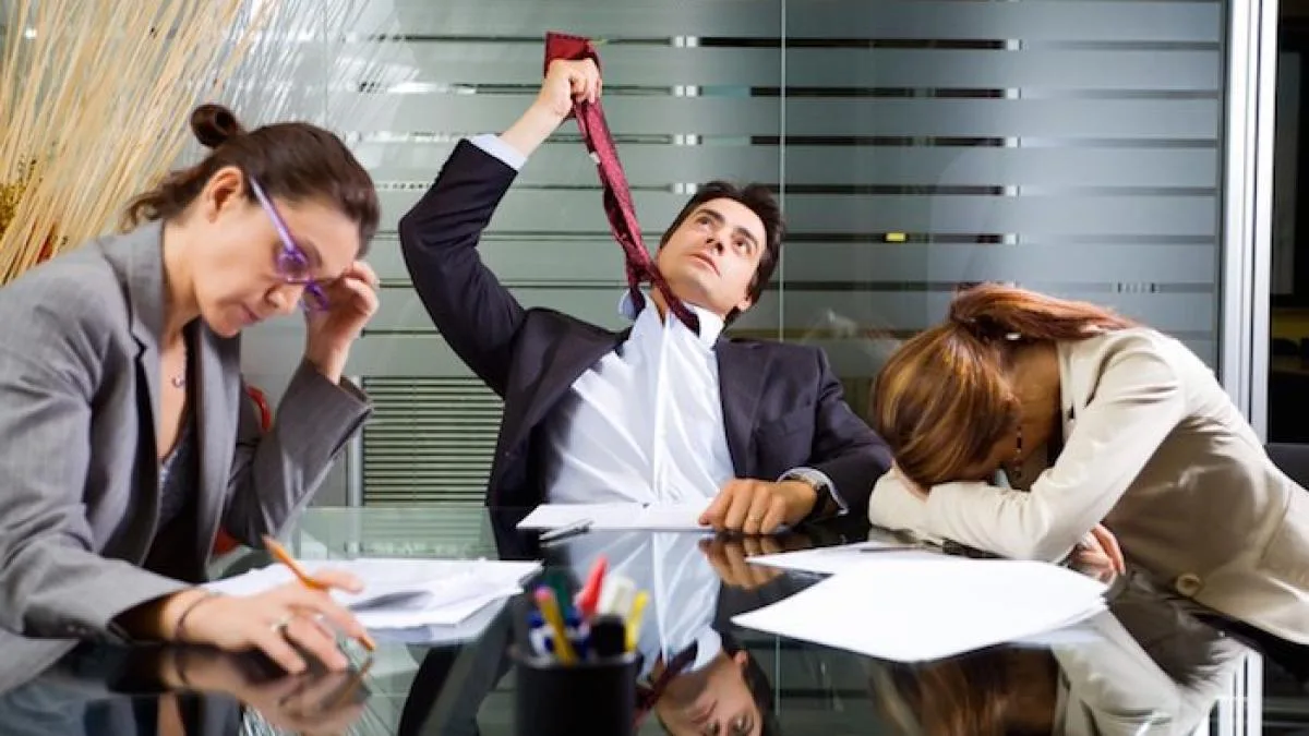 Tired meeting participants sit around a conference table while one person stretches red tape.